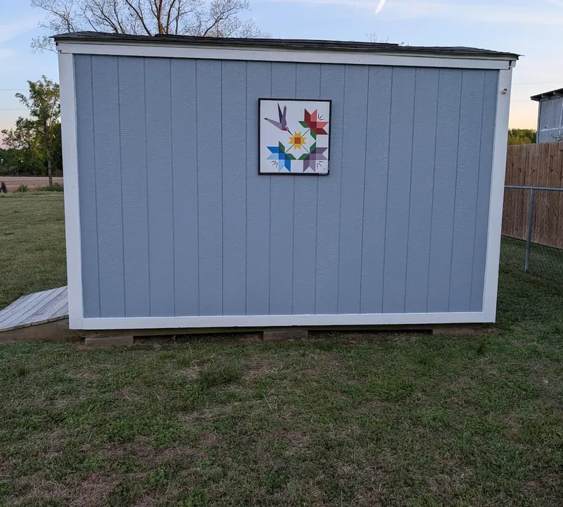 Barn quilt art hung on a backyard shed