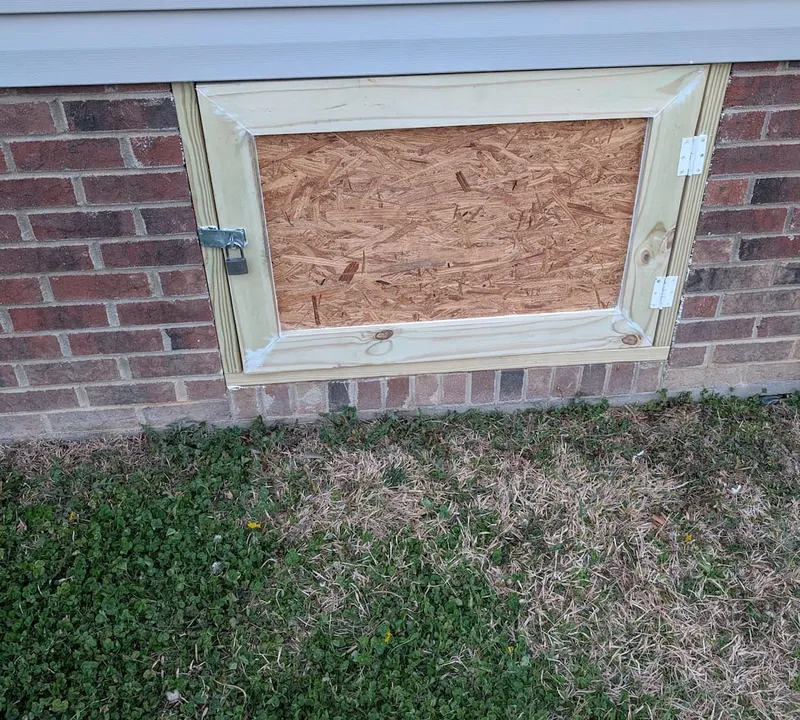 Repaired crawl space access door in a brick foundation